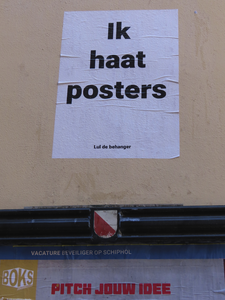 902280 Afbeelding van een poster met de tekst 'Ik haat posters', geplakt boven een gemeentelijk reclamebord in de ...